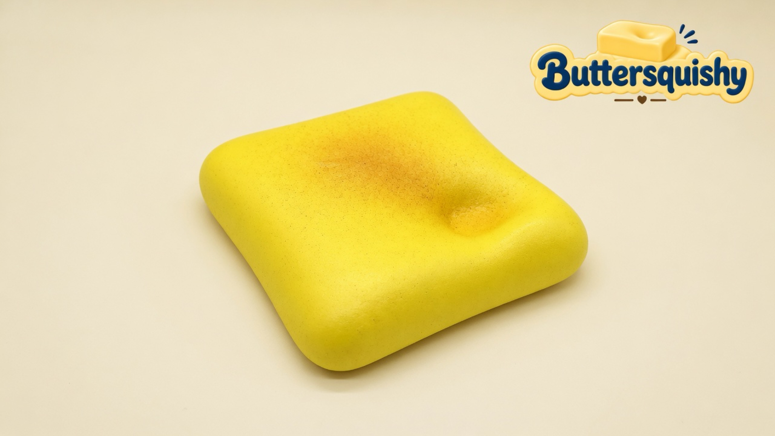 One yellow square Bread Toast Loaf with a golden toasted bloom and a circular dent on a light-yellow cream studio, Buttersquishy logo at upper right