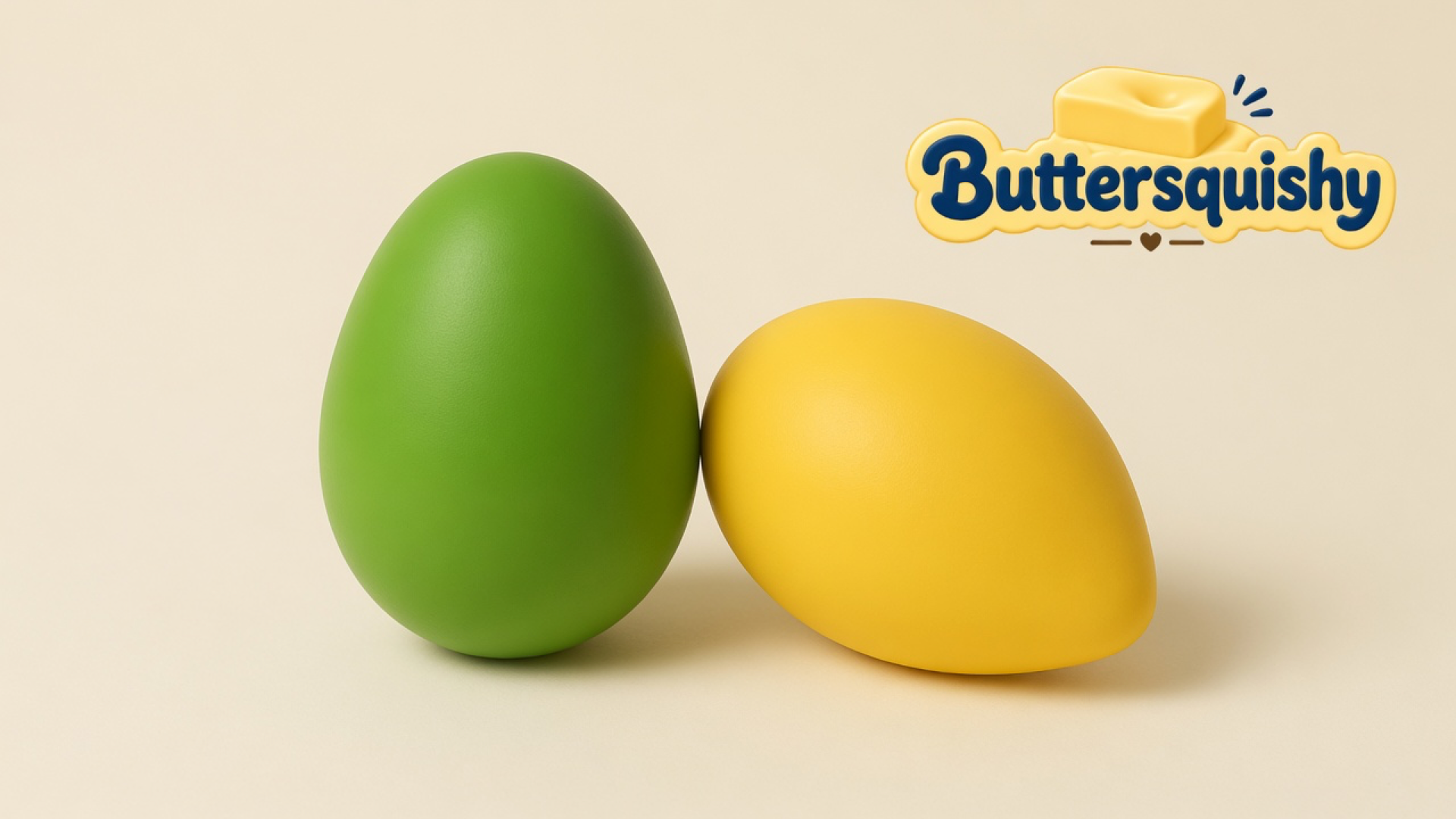 Leaf-green oval and mango-yellow teardrop Mixed Butter Pack toys on a soft light-yellow cream studio, Buttersquishy logo in the upper right