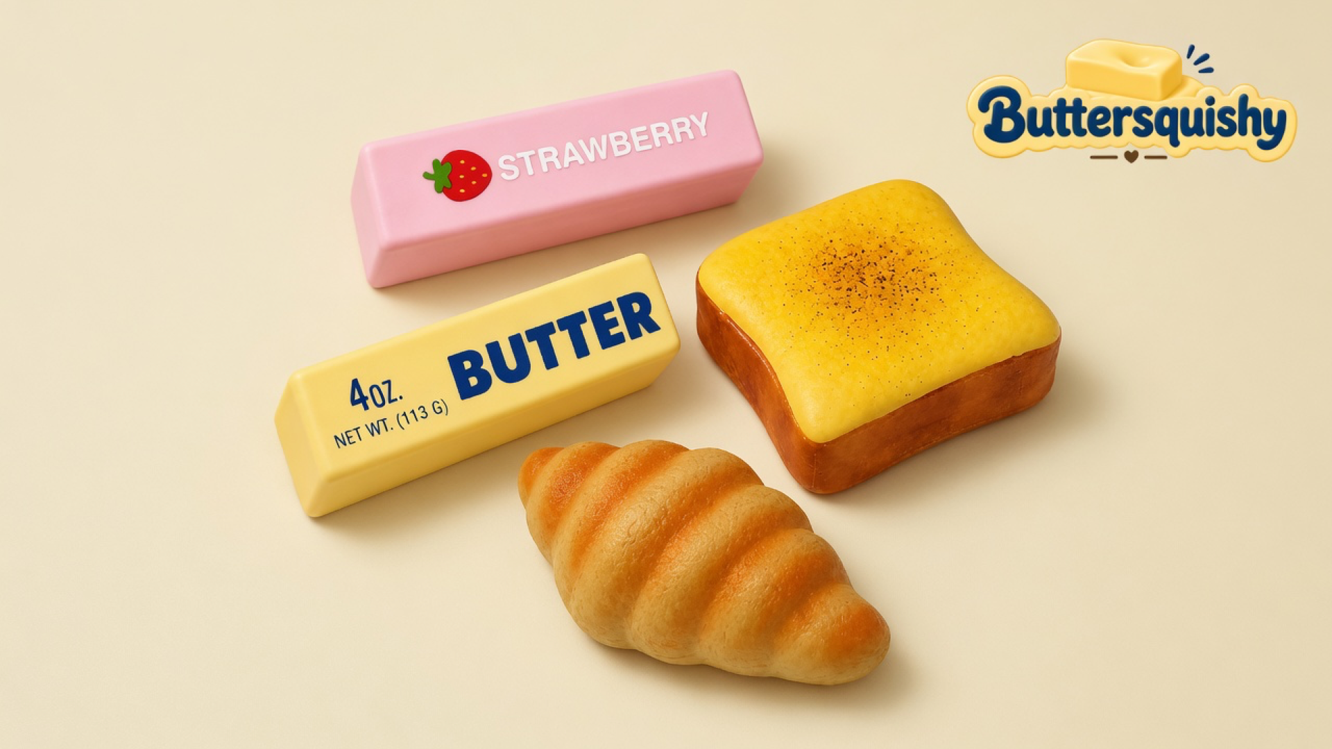 Pink STRAWBERRY stick, yellow BUTTER stick, toast slice, and croissant on a light-yellow cream studio, Buttersquishy logo upper right
