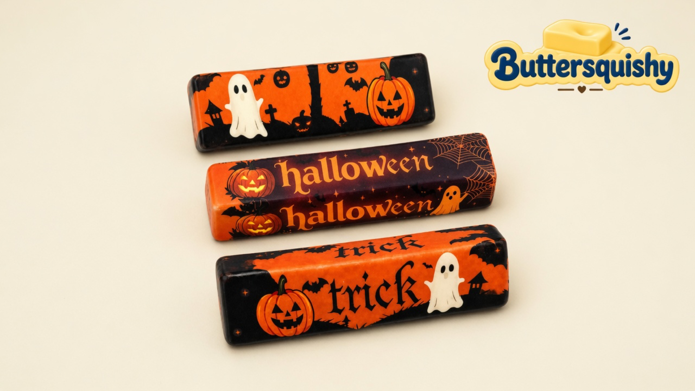 Three Halloween Ghost Butter sticks with ghost, pumpkin, halloween, and trick prints on a cream studio surface, Buttersquishy logo in the upper right