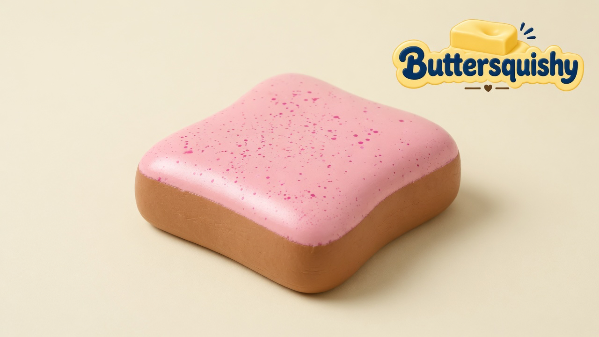 A square pink-frosted toast-style loaf with magenta speckle and a golden-tan crust on a light-yellow cream studio surface, Buttersquishy logo in the upper right