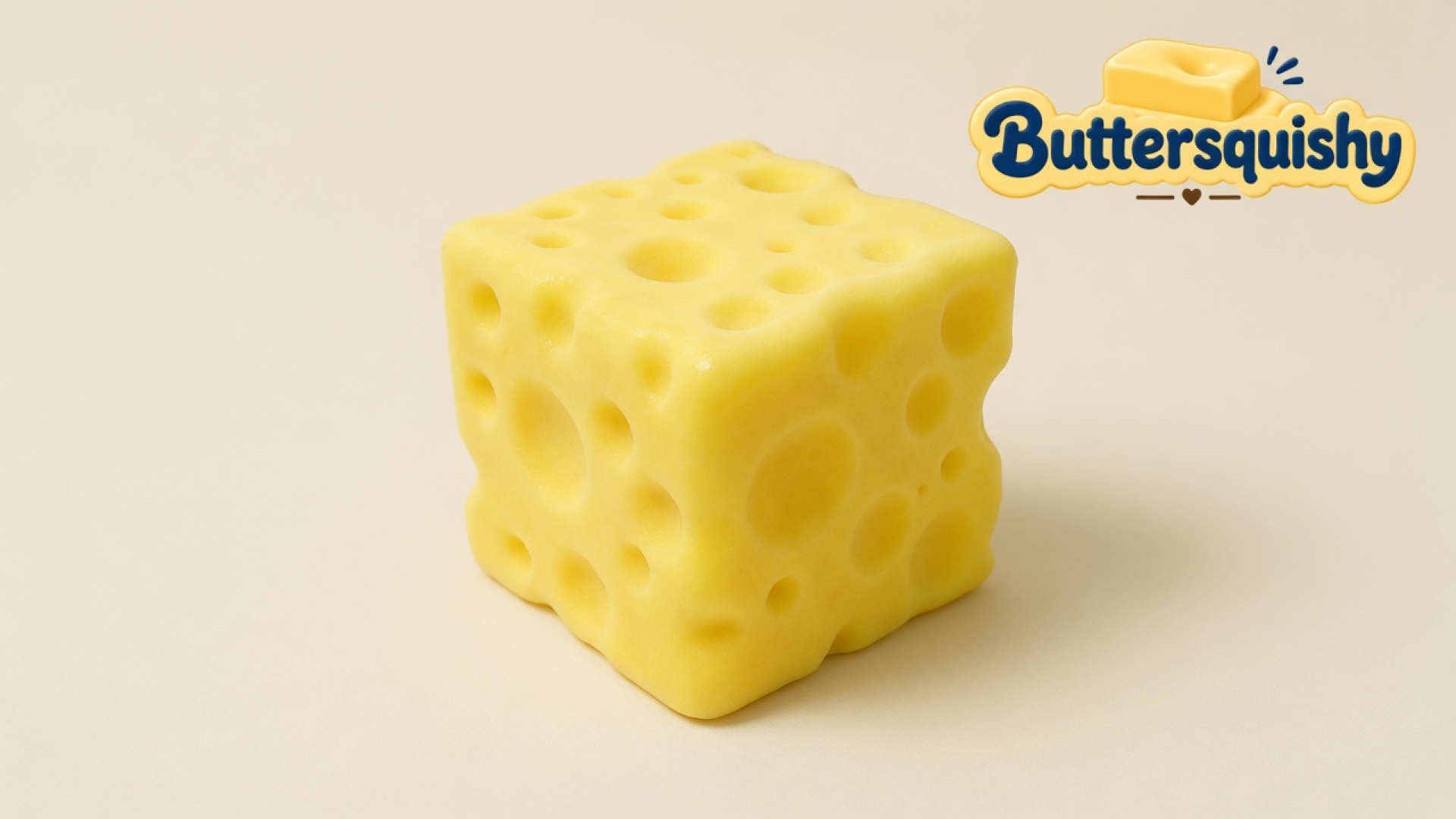 One cheddar-yellow Cheese Cube Loaf with mixed-size Swiss holes on a soft light-yellow cream studio surface, Buttersquishy logo in the upper right