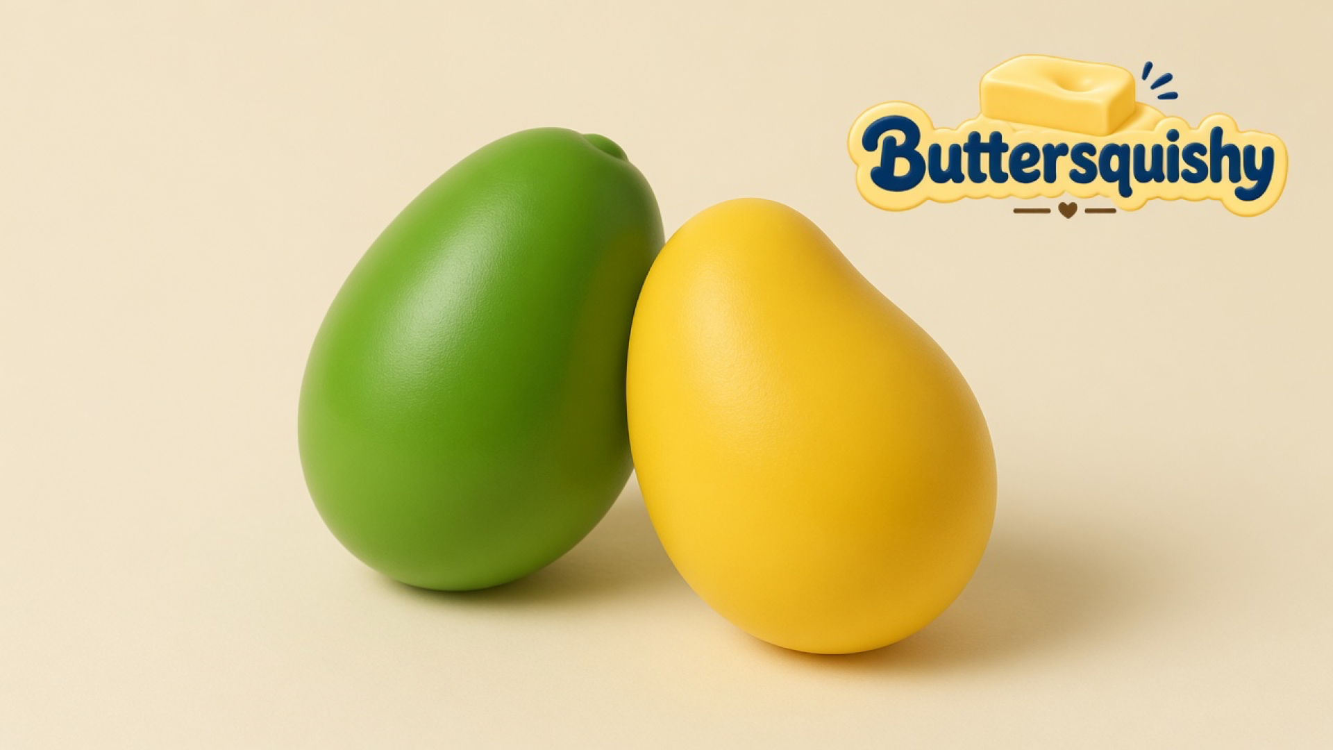 Green mango-shaped piece and yellow mango-shaped piece on a light-yellow cream studio surface, Buttersquishy logo at upper right