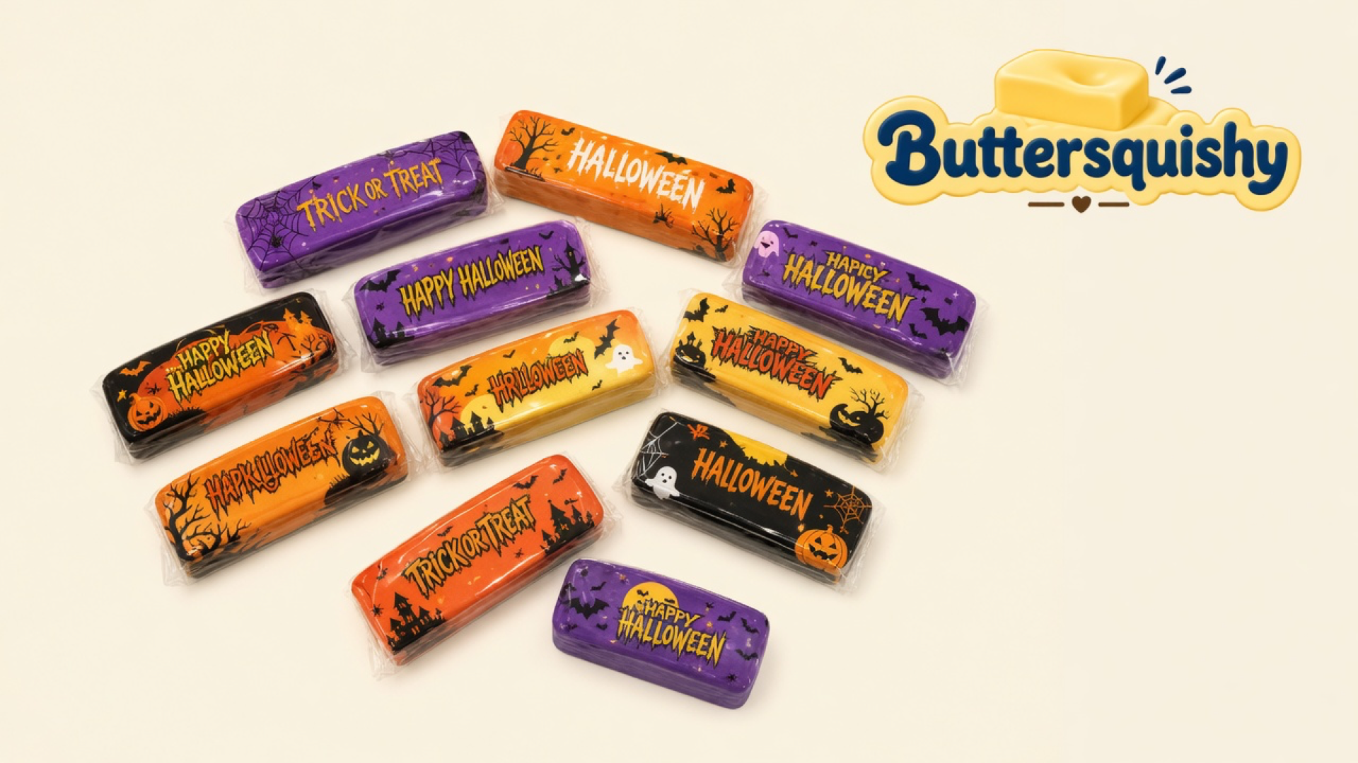 Twelve wrapped Halloween Ghost Butter sticks on a light cream studio surface, Buttersquishy logo at upper right
