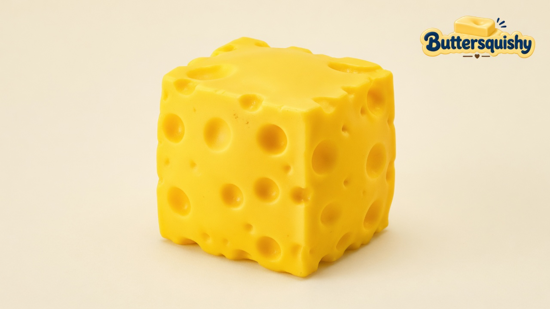 One bright yellow Cheese Cube Loaf with mixed-size holes on a light-yellow cream studio surface, Buttersquishy logo at upper right