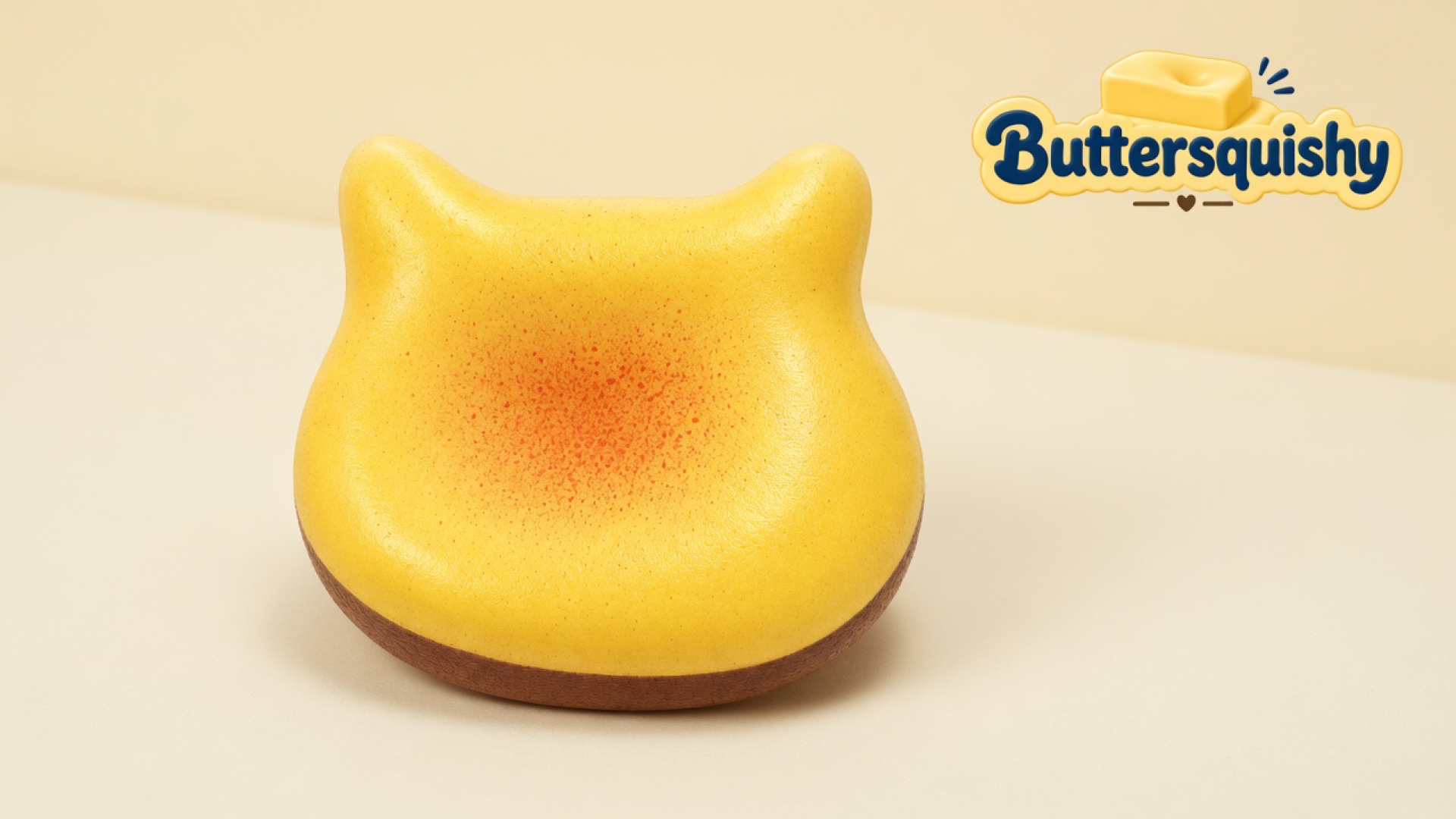 One golden-yellow cat-ear Bread Toast Loaf with an orange-red blush and a brown crust band on a light-yellow cream studio, Buttersquishy logo at upper right