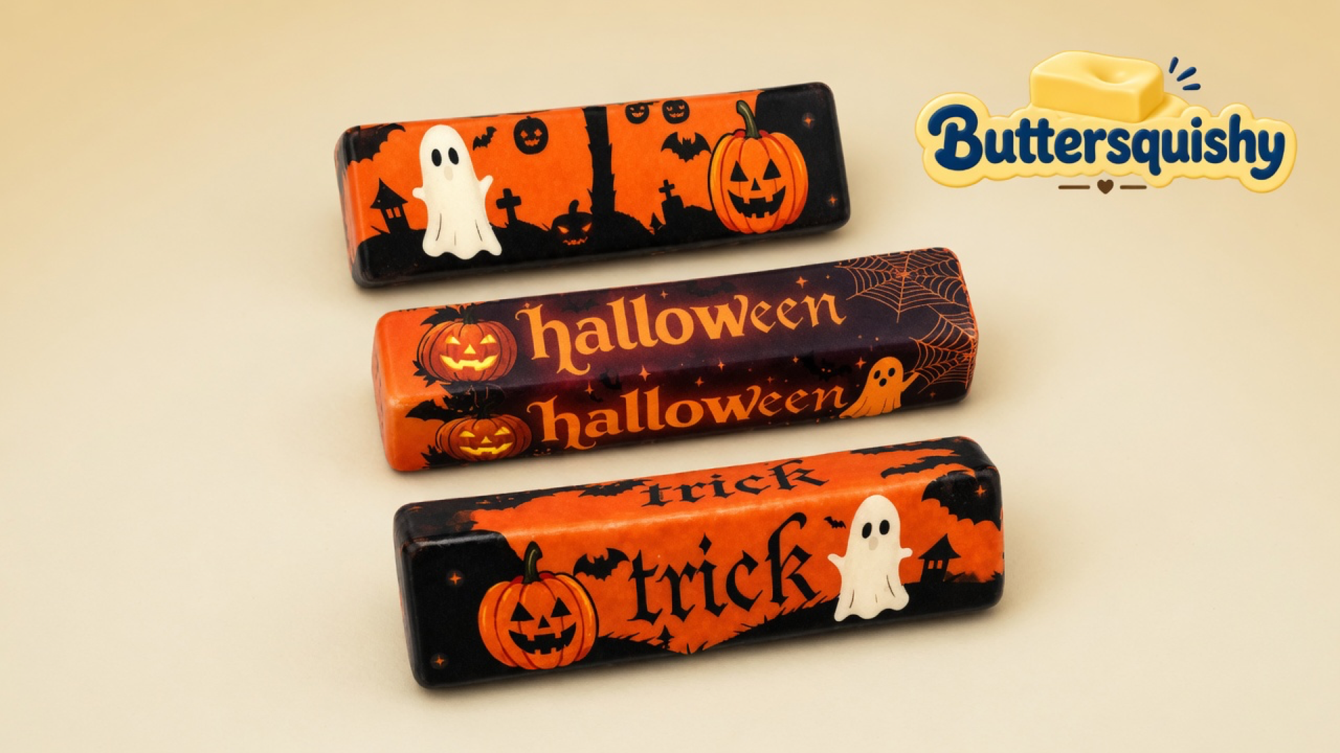 Three Halloween Ghost Butter sticks with ghost, pumpkin, halloween, and trick prints on a cream studio surface, Buttersquishy logo at upper right