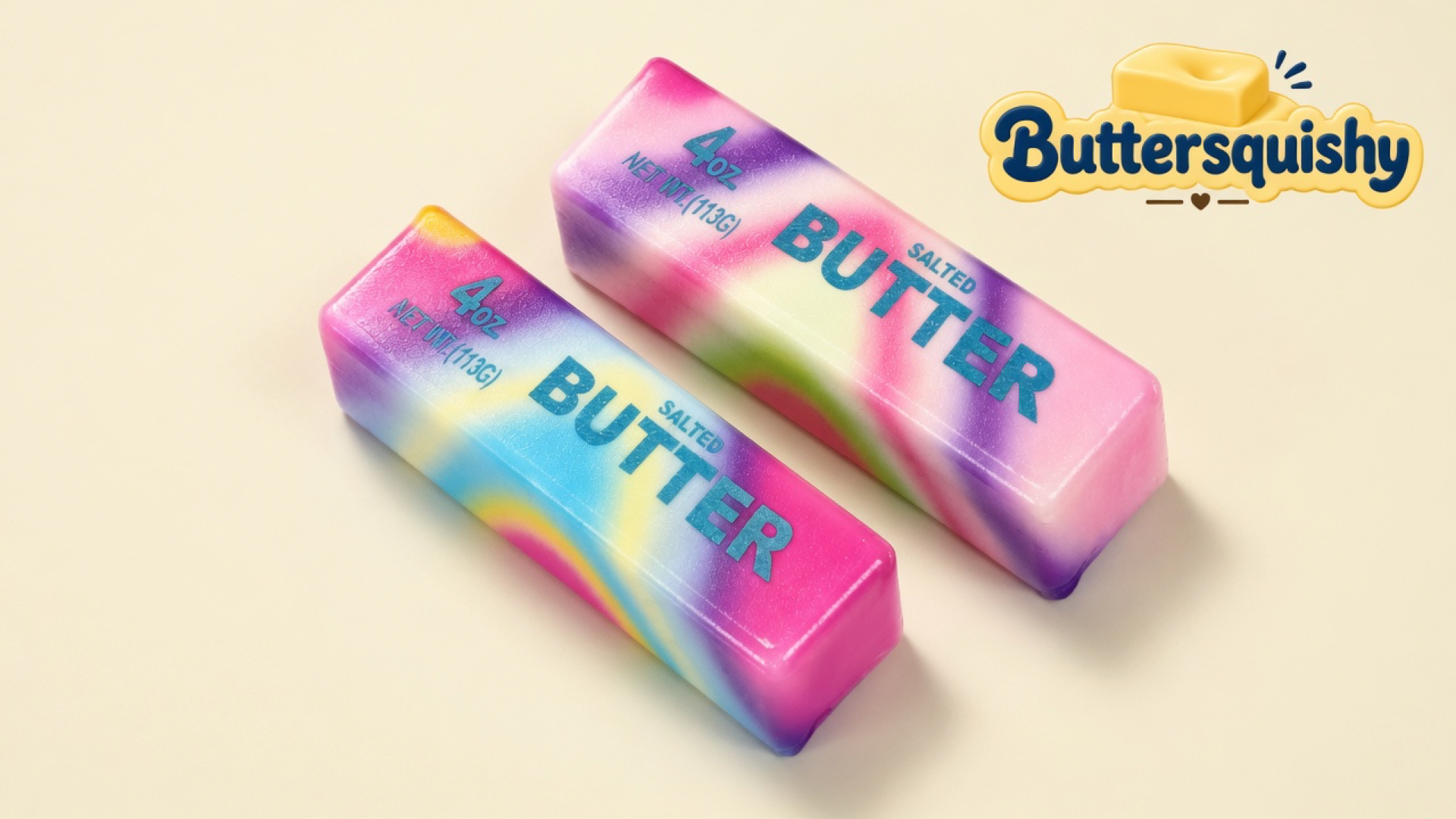Two pink-purple-blue-yellow tie-dye butter sticks printed 4oz NET WT.(113G) BUTTER SALTED on a light-yellow cream studio surface, Buttersquishy logo in the upper right