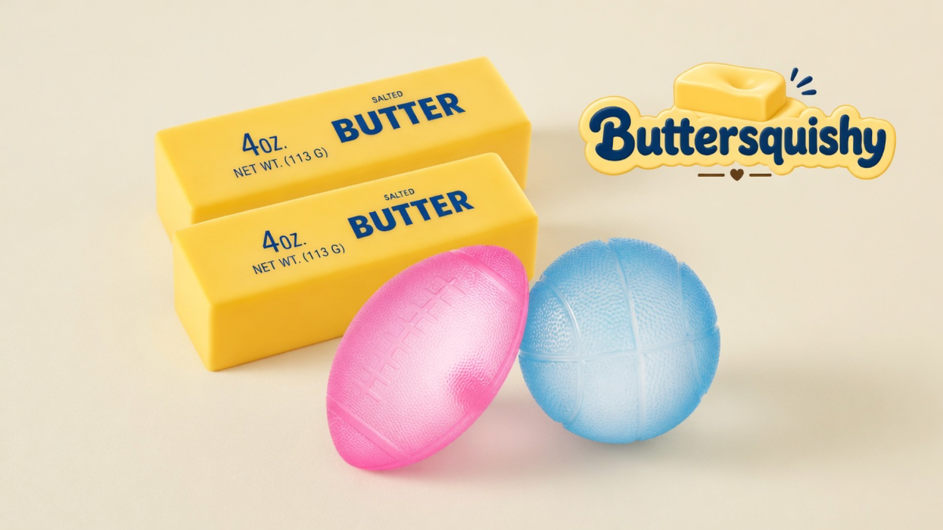 Two yellow SALTED BUTTER sticks, a pink football, and a blue basketball on a light-yellow cream studio surface, Buttersquishy logo in the upper right