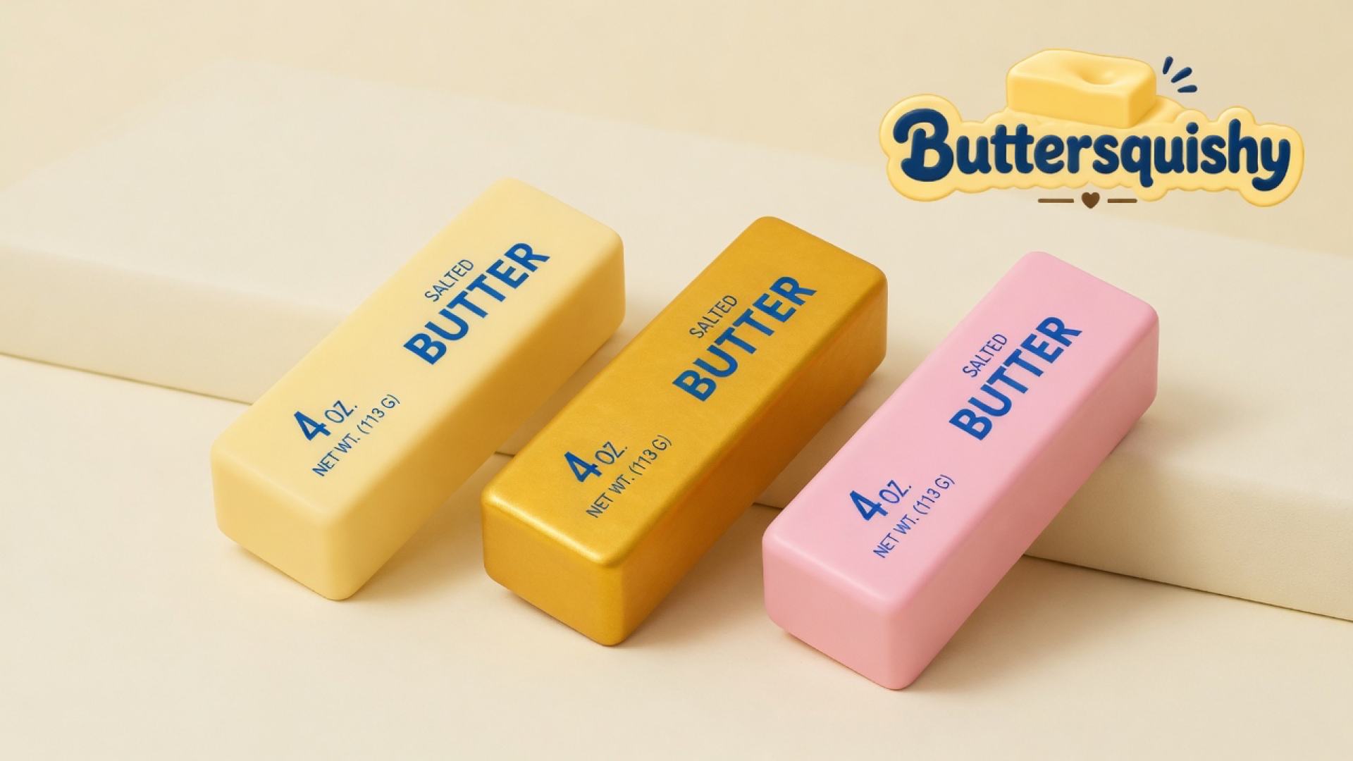 Three Sunset Trio Butter sticks in cream, gold, and pink with navy SALTED BUTTER prints on a cream studio platform, Buttersquishy logo in the upper right