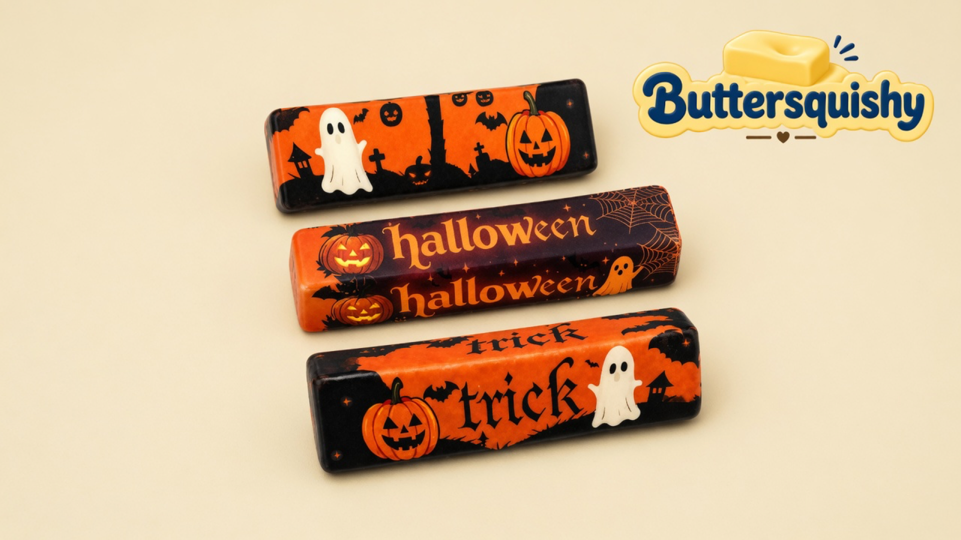Three Halloween Ghost Butter sticks with ghost, pumpkin, halloween, and trick prints on a cream studio surface, Buttersquishy logo in the upper right