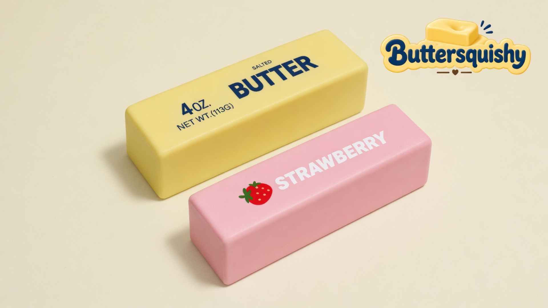 Pale yellow SALTED BUTTER loaf and pink STRAWBERRY loaf on a light-yellow cream studio surface, Buttersquishy logo in the upper right