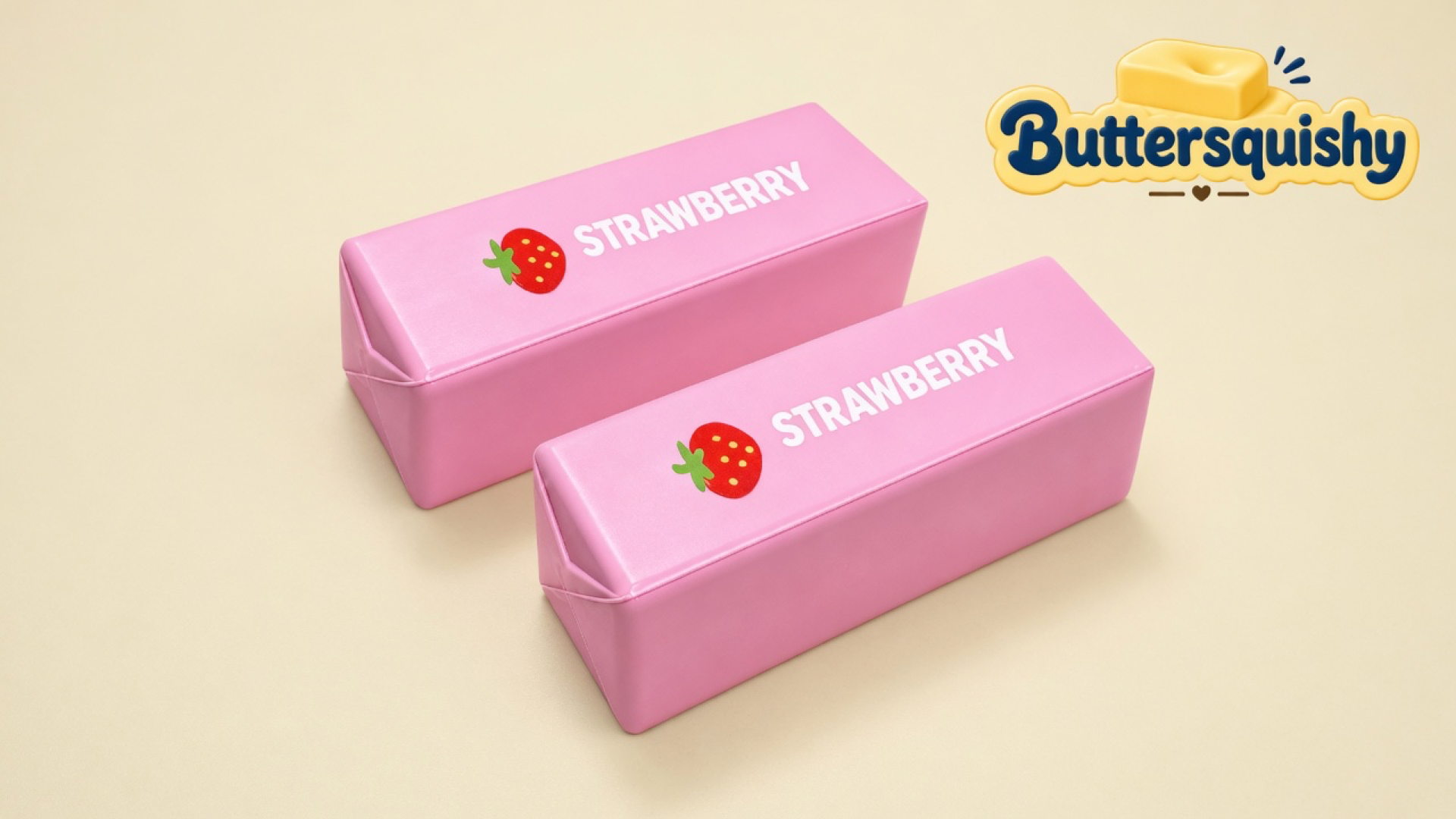 Two glossy pink strawberry-print butter-stick squishies on a light-yellow cream studio surface, Buttersquishy logo in the upper right