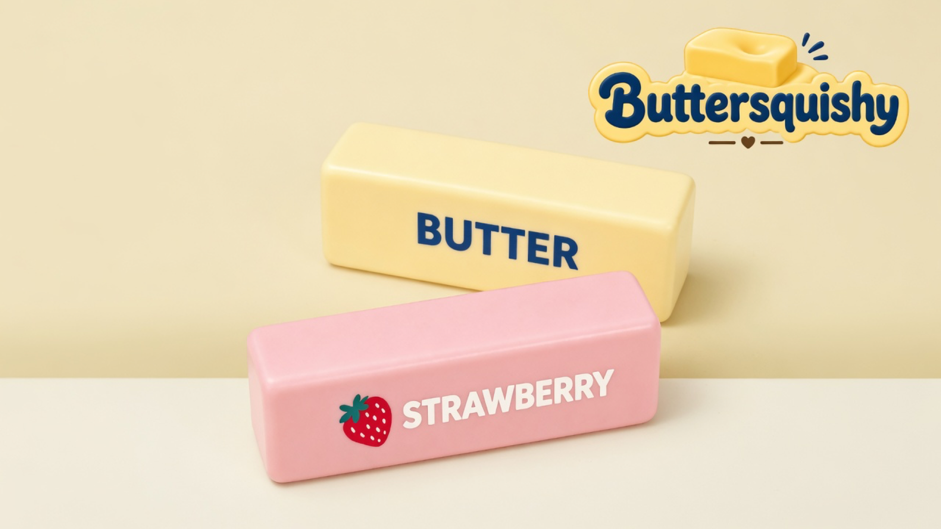 Pale yellow BUTTER loaf and pink STRAWBERRY loaf on a light-yellow cream studio surface, Buttersquishy logo in the upper right