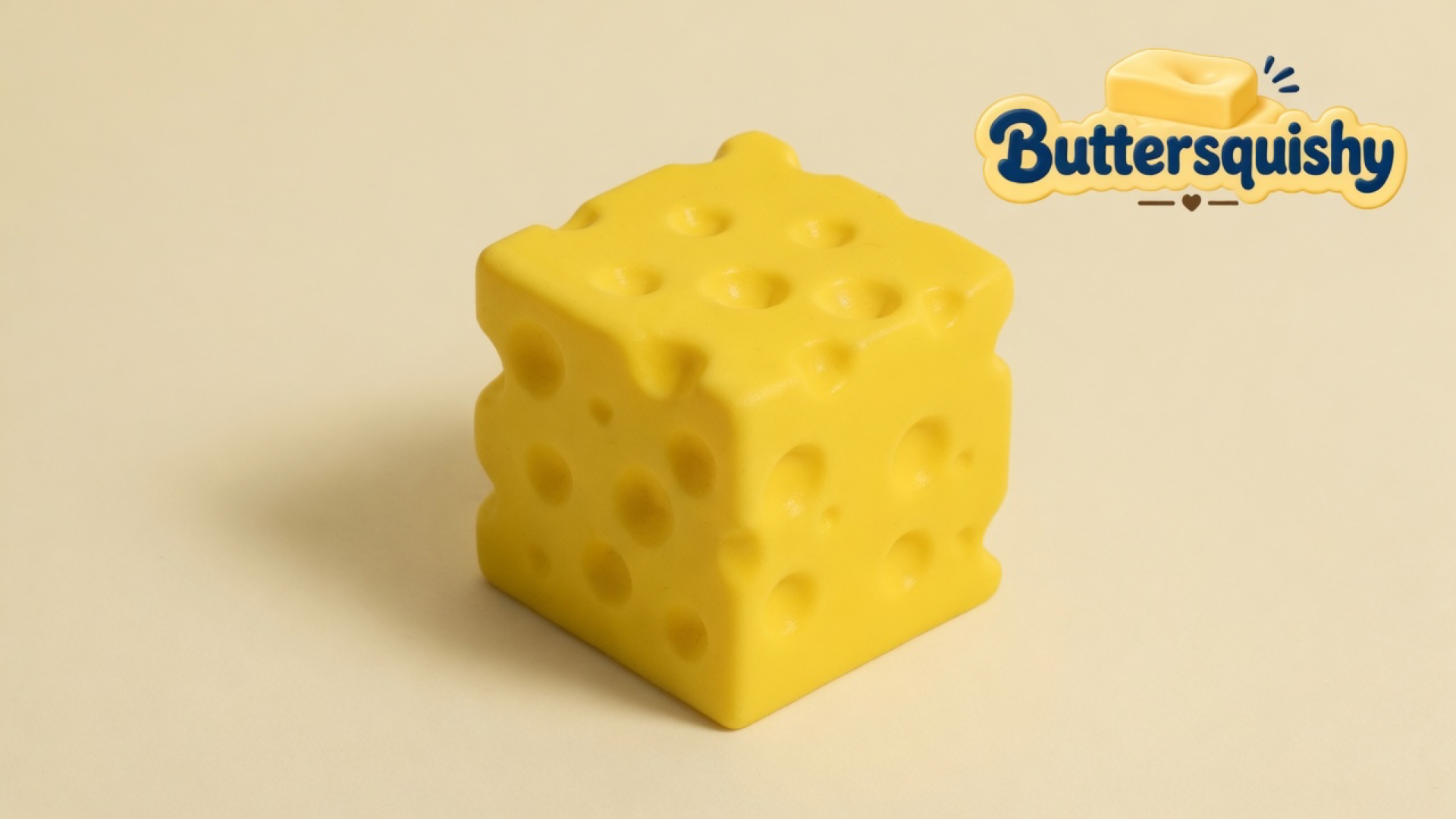 One lemon-yellow Swiss-hole Cheese Cube Loaf on a light-yellow cream studio, Buttersquishy logo at upper right