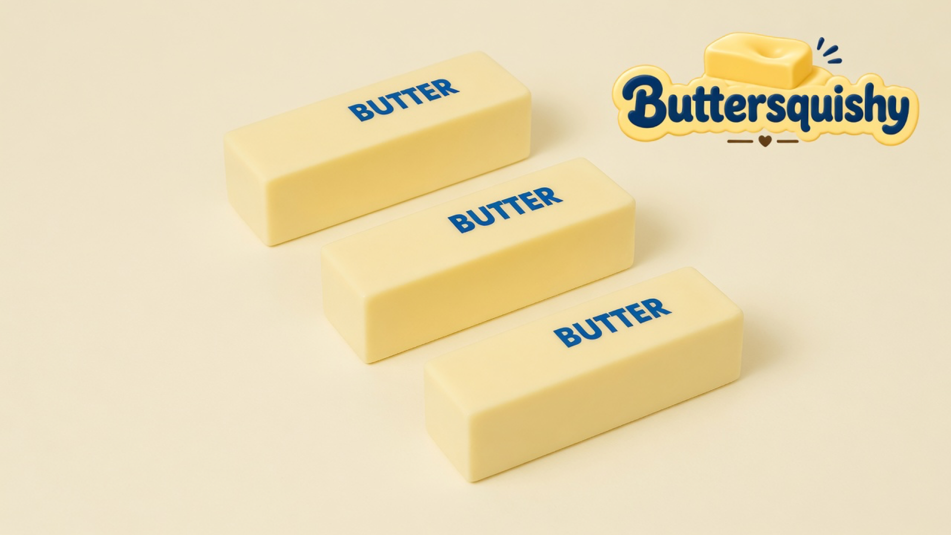 Three pale yellow rectangular butter sticks printed BUTTER on a light-yellow cream studio surface, Buttersquishy logo in the upper right