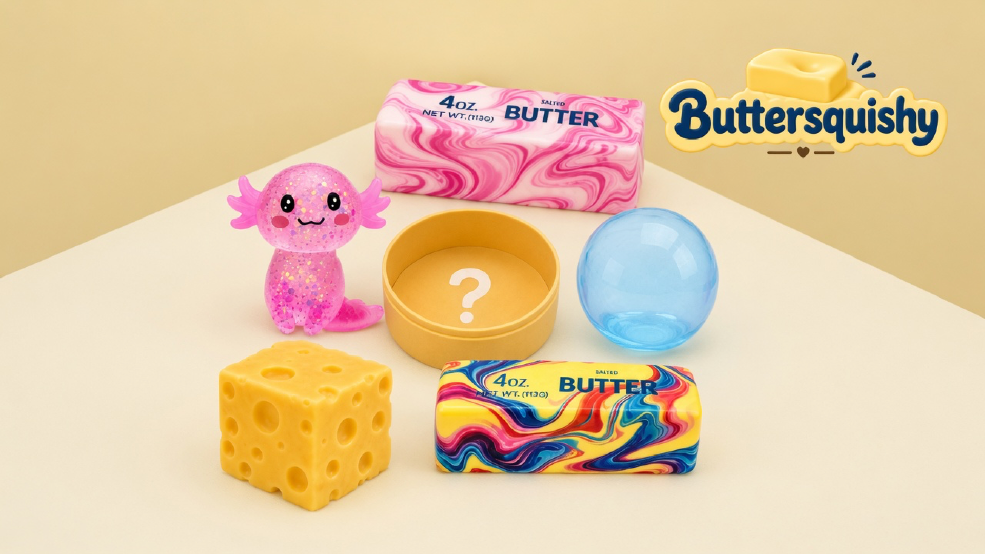 Pink glitter axolotl, pink marble SALTED BUTTER stick, yellow cup with a question mark, translucent blue orb, holey cheese cube, and yellow rainbow-marble SALTED BUTTER stick on a light-yellow cream studio table, Buttersquishy logo in the upper right