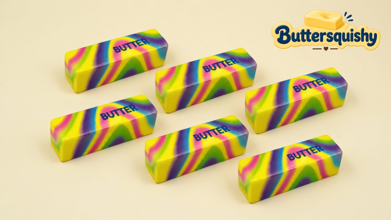 Six neon-swirl butter sticks printed with navy BUTTER on a cream studio surface, Buttersquishy logo in the upper right