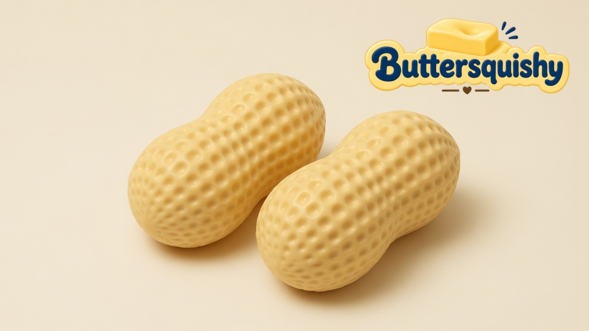 Two pale yellow dimpled peanut-shell squishies on a cream studio surface, Buttersquishy logo in the upper right