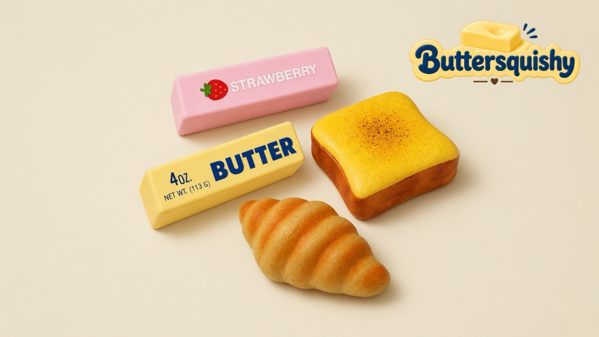 Four Bread Toast Loaf toys — a pink strawberry stick, a yellow butter stick, a toasted slice, and a croissant — on a light-yellow cream studio surface, Buttersquishy logo in the upper right