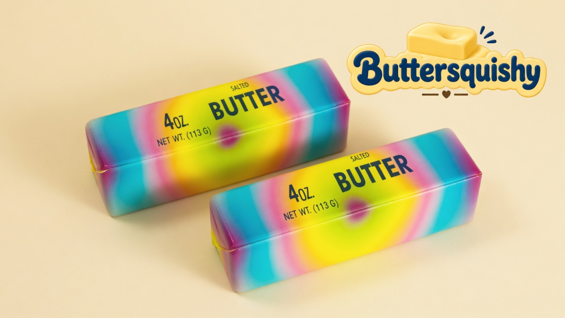 Two Candy Gradient Butter sticks with cyan-to-pink-to-yellow melts and navy SALTED BUTTER type on a light-yellow cream studio, Buttersquishy logo in the upper right