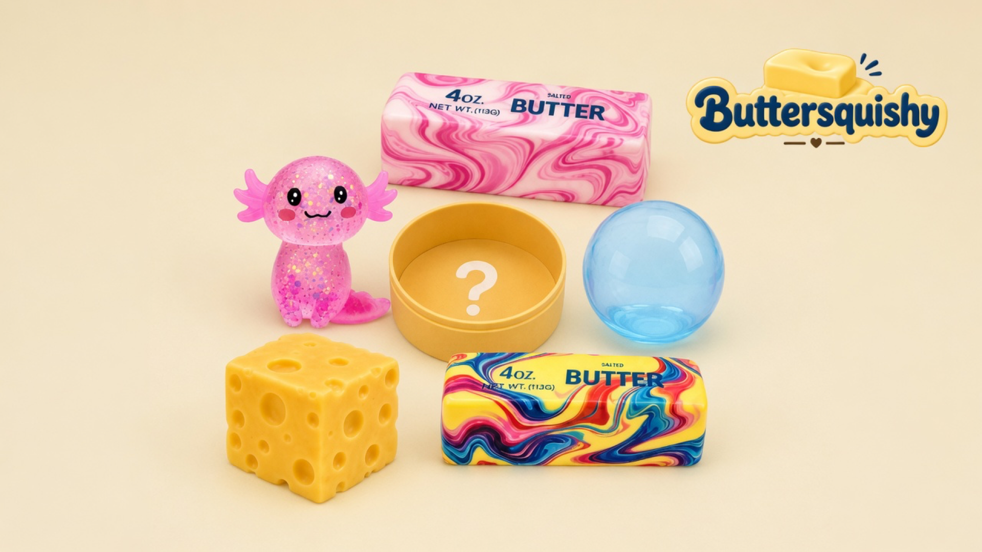 Six-piece Cheese Cube Loaf 6-Pack on a light-yellow cream studio surface: pink glitter axolotl, pink marble butter stick, yellow mystery tin, blue sphere, yellow cheese cube, and rainbow swirl butter stick, Buttersquishy logo in the upper right