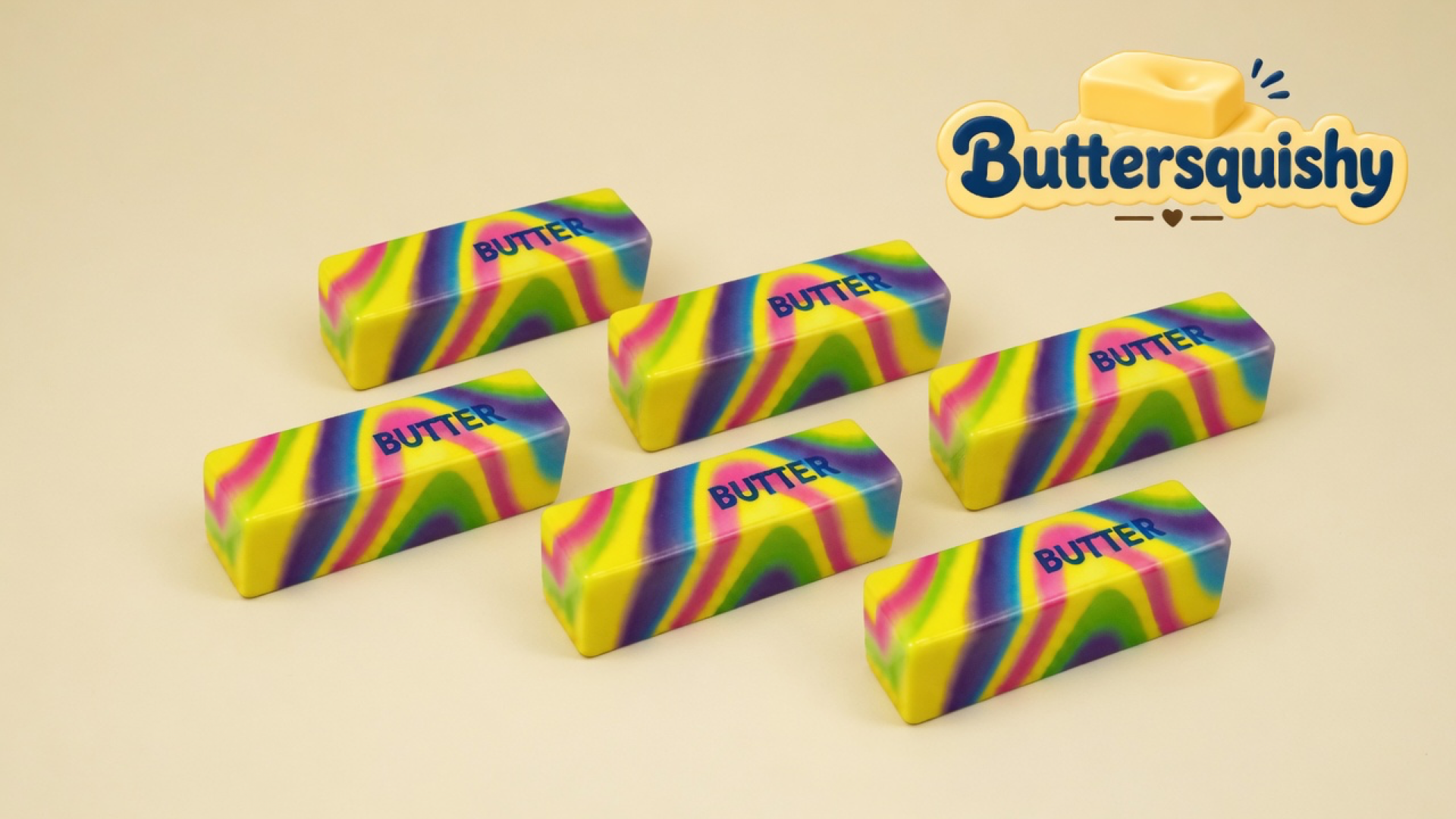Six Neon Swirl Butter sticks with blended yellow-magenta-purple-lime swirls and navy BUTTER print on a light-yellow cream studio surface, Buttersquishy logo in the upper right