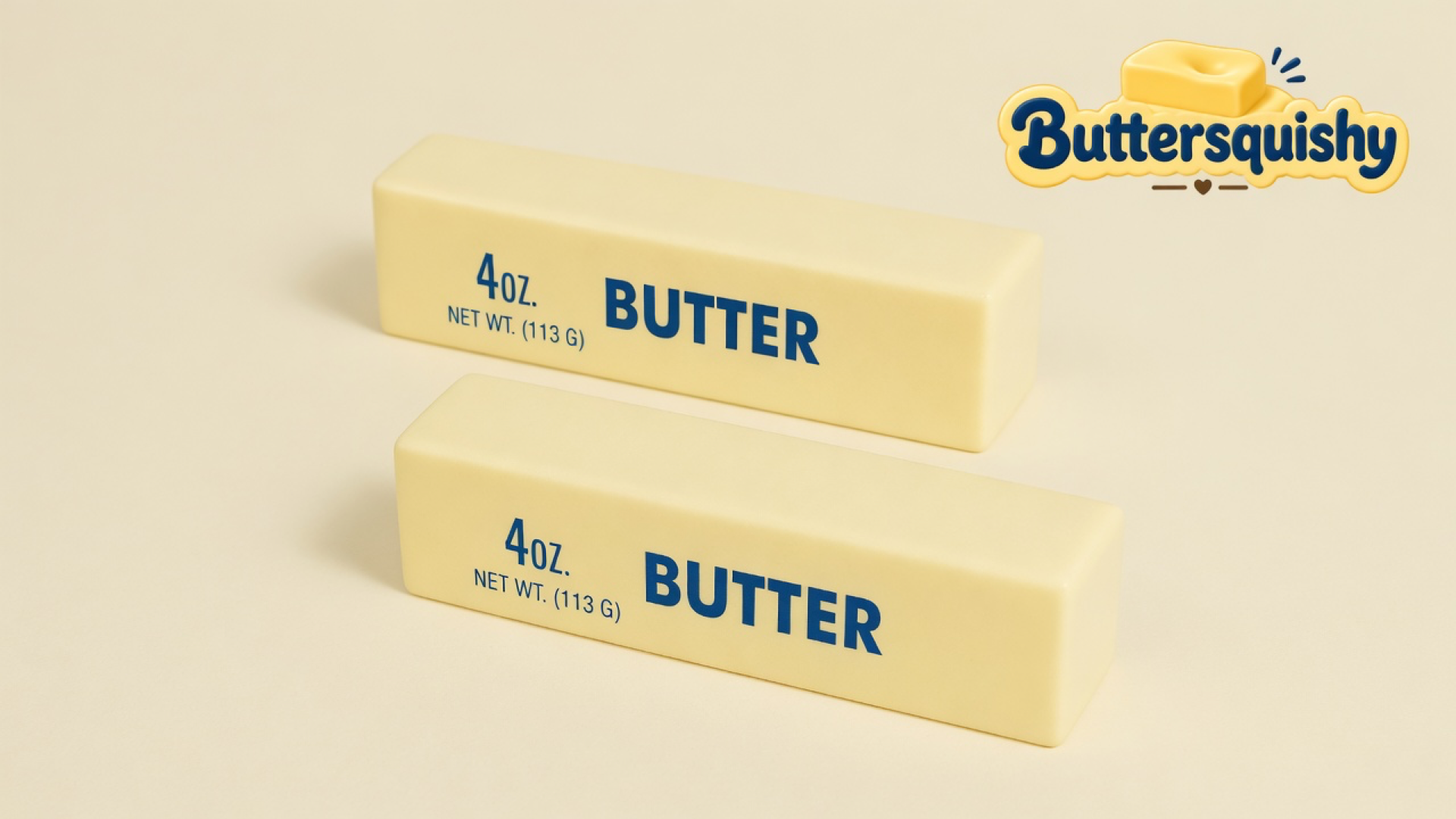 Two matching pale-yellow butter-stick toys printed with navy 4oz and BUTTER on a soft light-yellow cream studio table, Buttersquishy logo in the upper right