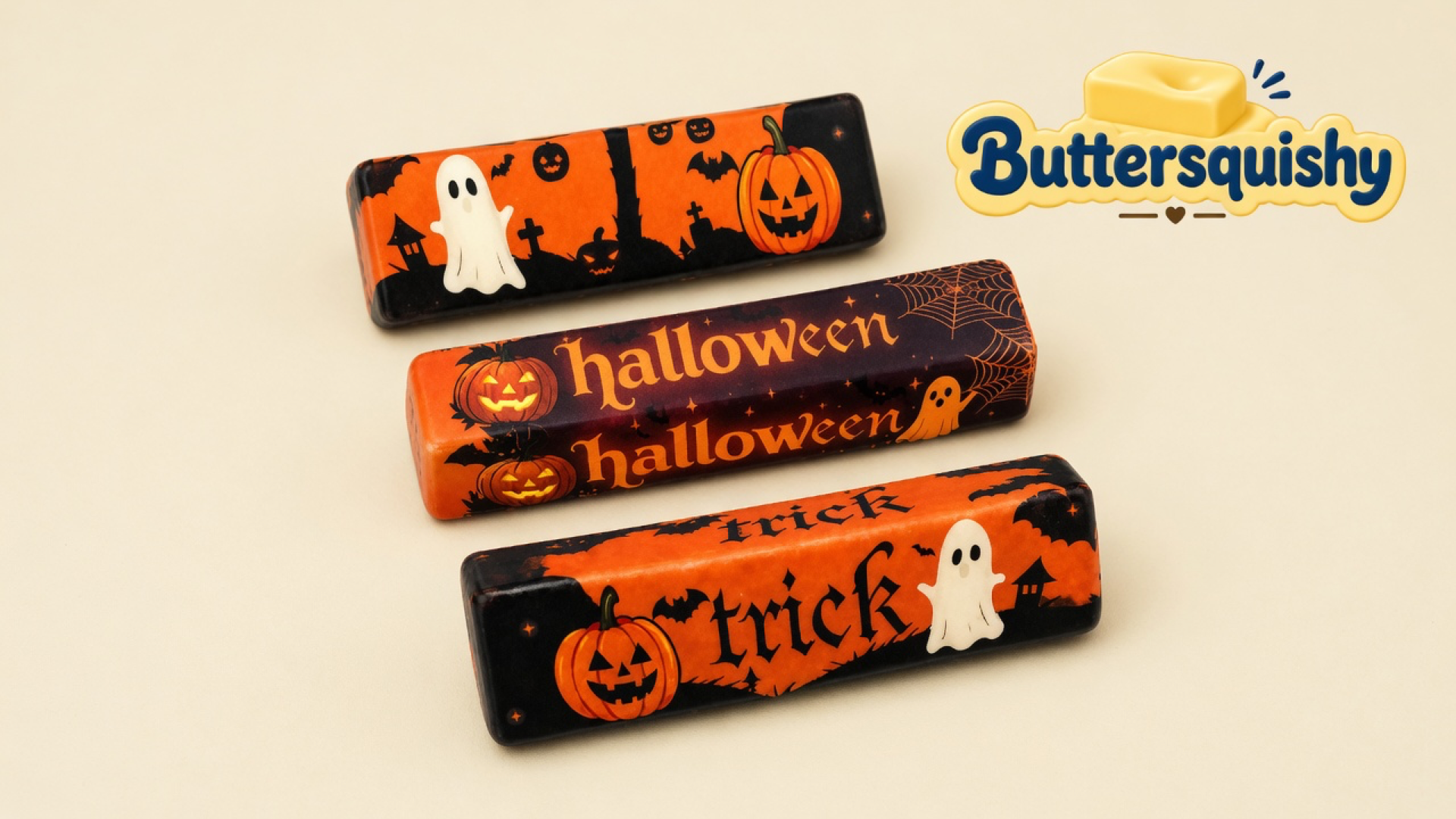 Three Halloween Ghost Butter sticks with ghost, pumpkin, halloween, and trick prints on a cream studio surface, Buttersquishy logo in the upper right