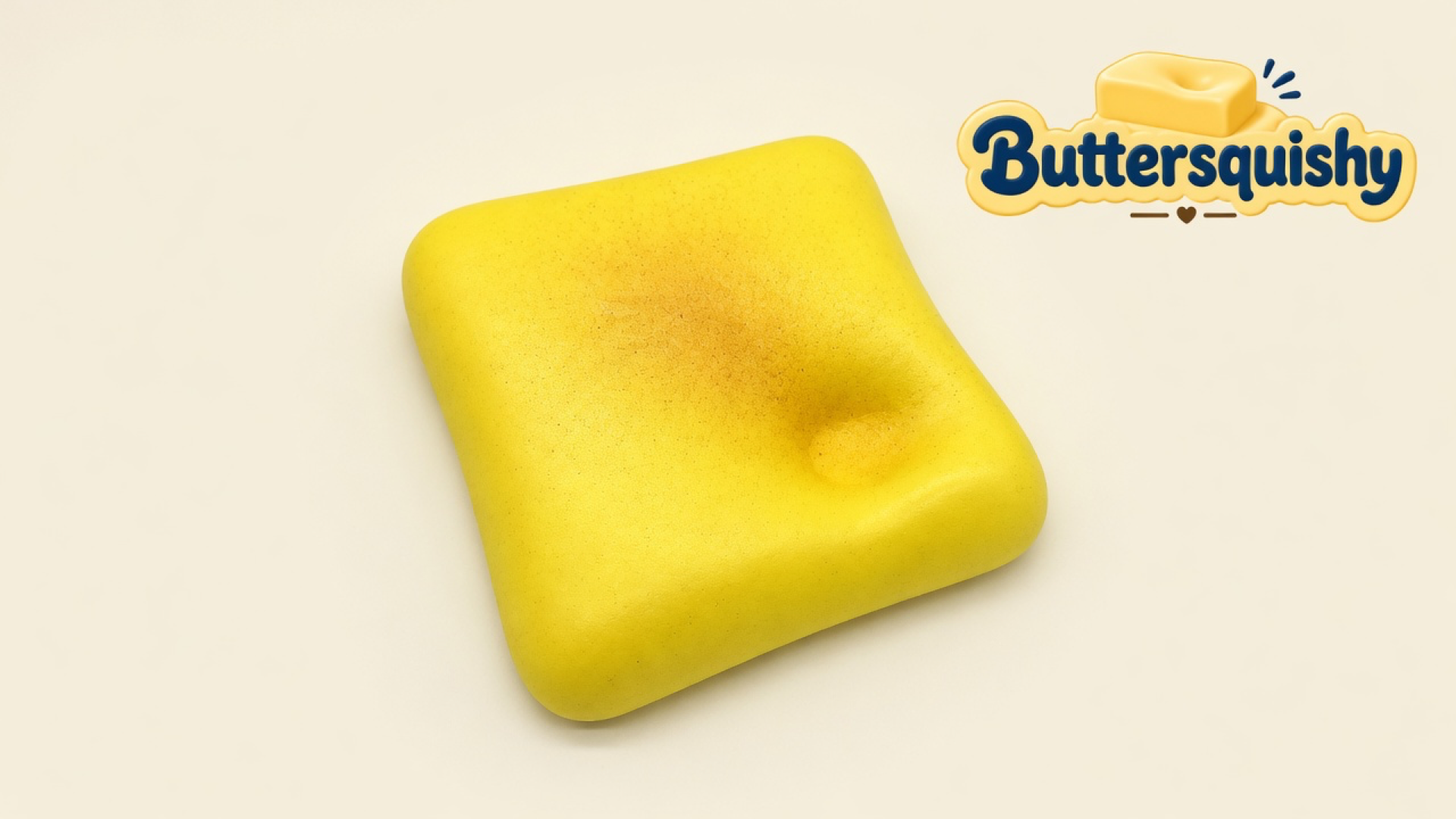 A yellow toast-shaped loaf with a golden-brown toasted center and a thumb dent on a light-yellow cream studio surface, Buttersquishy logo in the upper right