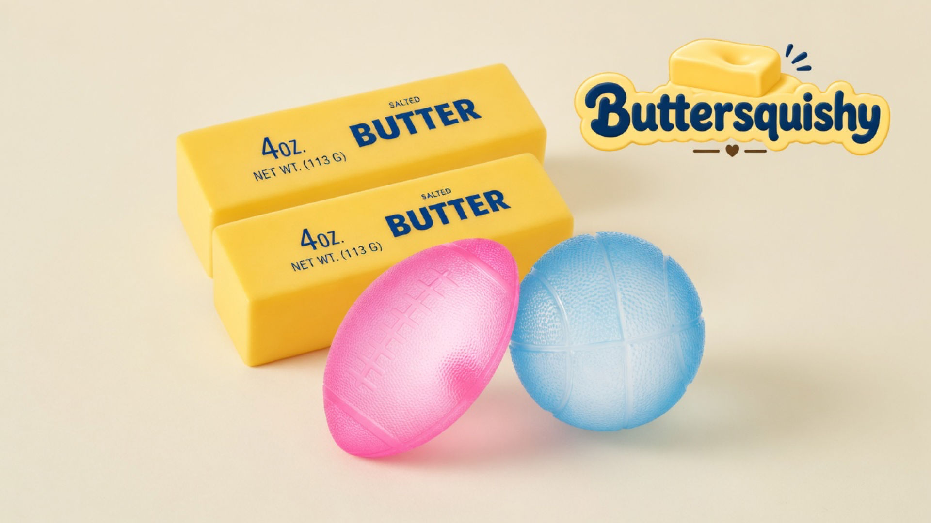 Two yellow SALTED BUTTER sticks stacked beside a pink football and a light-blue basketball on a light-yellow cream studio sweep, Buttersquishy logo once at the upper right