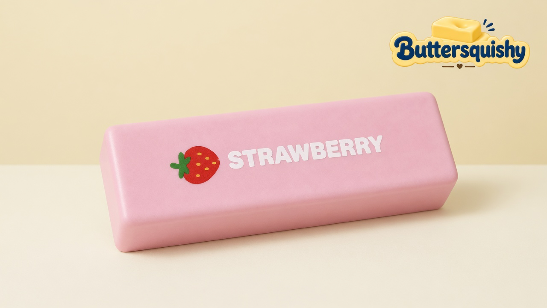 One pale-pink Strawberry Butter Stick with a cartoon berry and white STRAWBERRY type on a light-yellow cream studio surface, Buttersquishy logo in the upper right