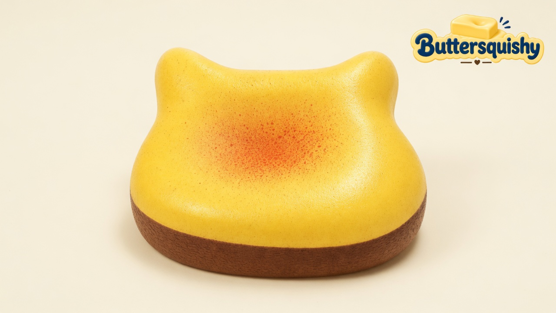 One yellow Bread Toast Loaf bun with an orange-red blush well and a brown crust band on a light-yellow cream studio, Buttersquishy logo in the upper right