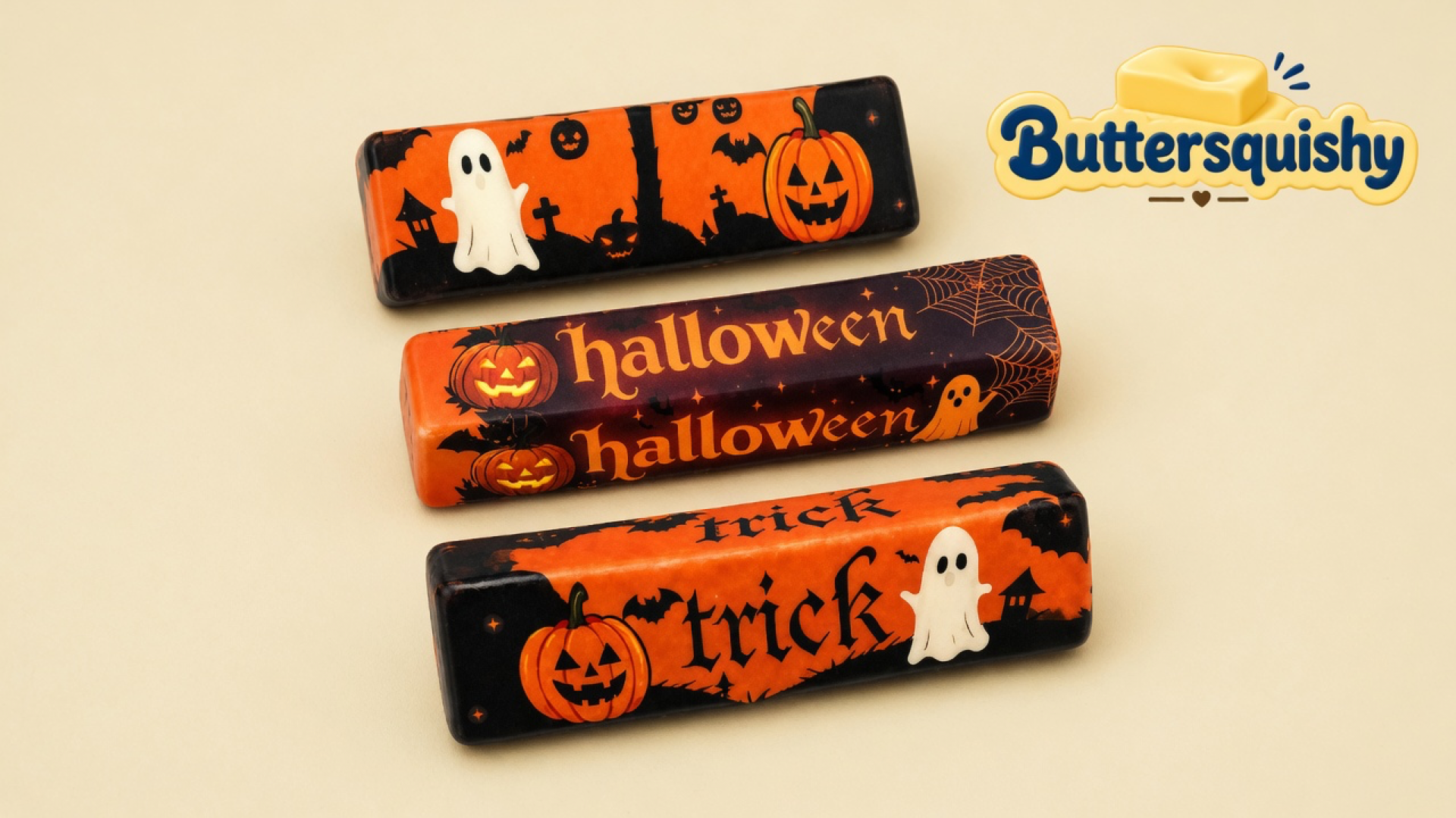 Three Halloween Ghost Butter sticks with ghost, pumpkin, halloween, and trick prints on a cream studio surface, Buttersquishy logo in the upper right