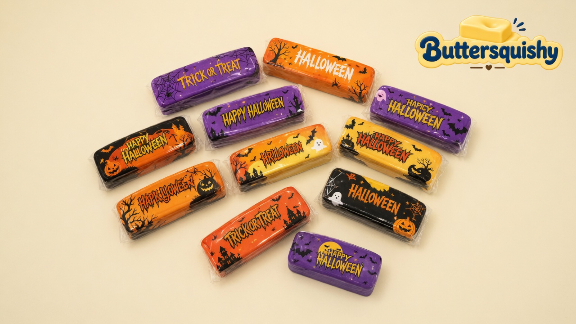 Twelve individually wrapped Halloween Ghost Butter sticks on a cream studio surface, with the Buttersquishy logo in the upper right