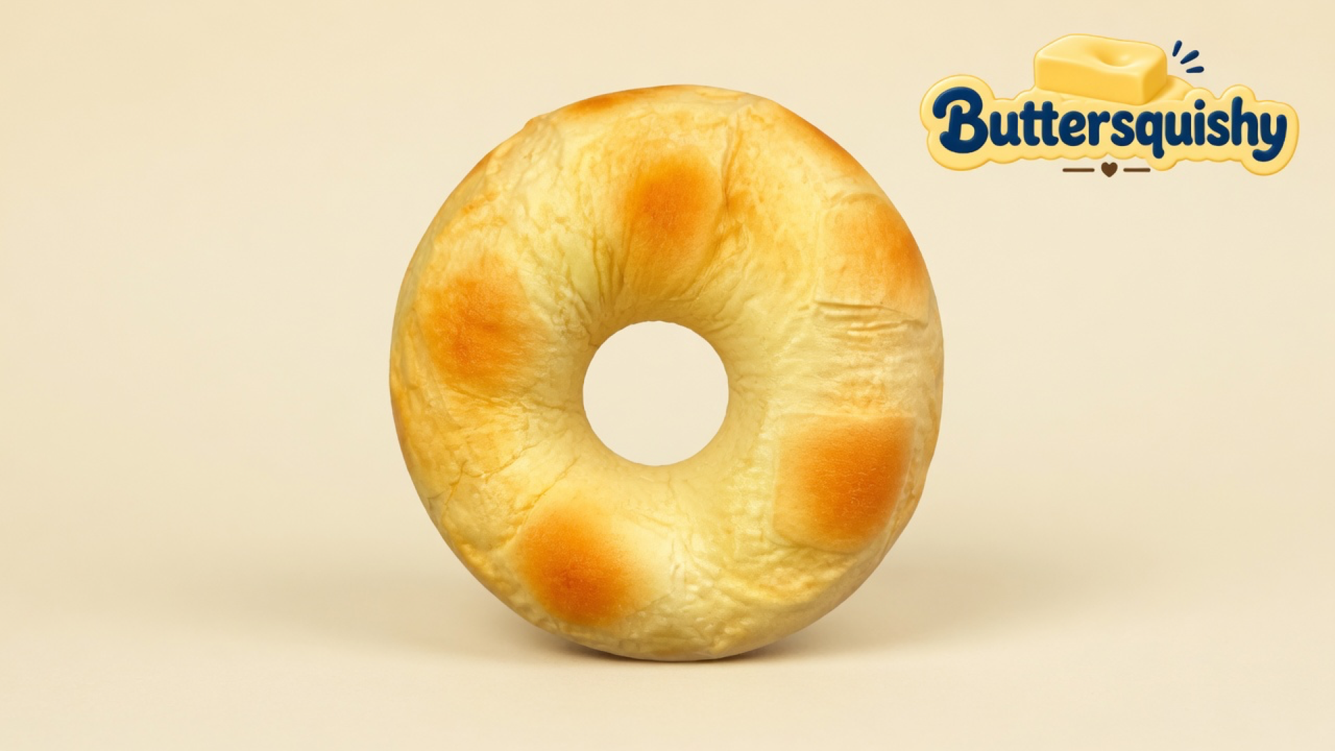One ring-shaped golden Bread Toast Loaf with four toasted ovals and an empty center hole on a light-yellow cream studio, Buttersquishy logo in the upper right