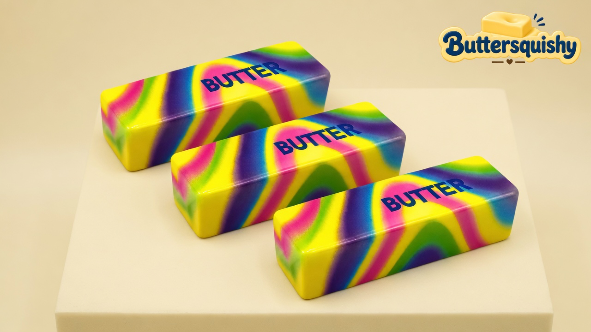 Three neon yellow-pink-green-purple swirl butter sticks printed BUTTER on a light-yellow cream studio block, Buttersquishy logo in the upper right