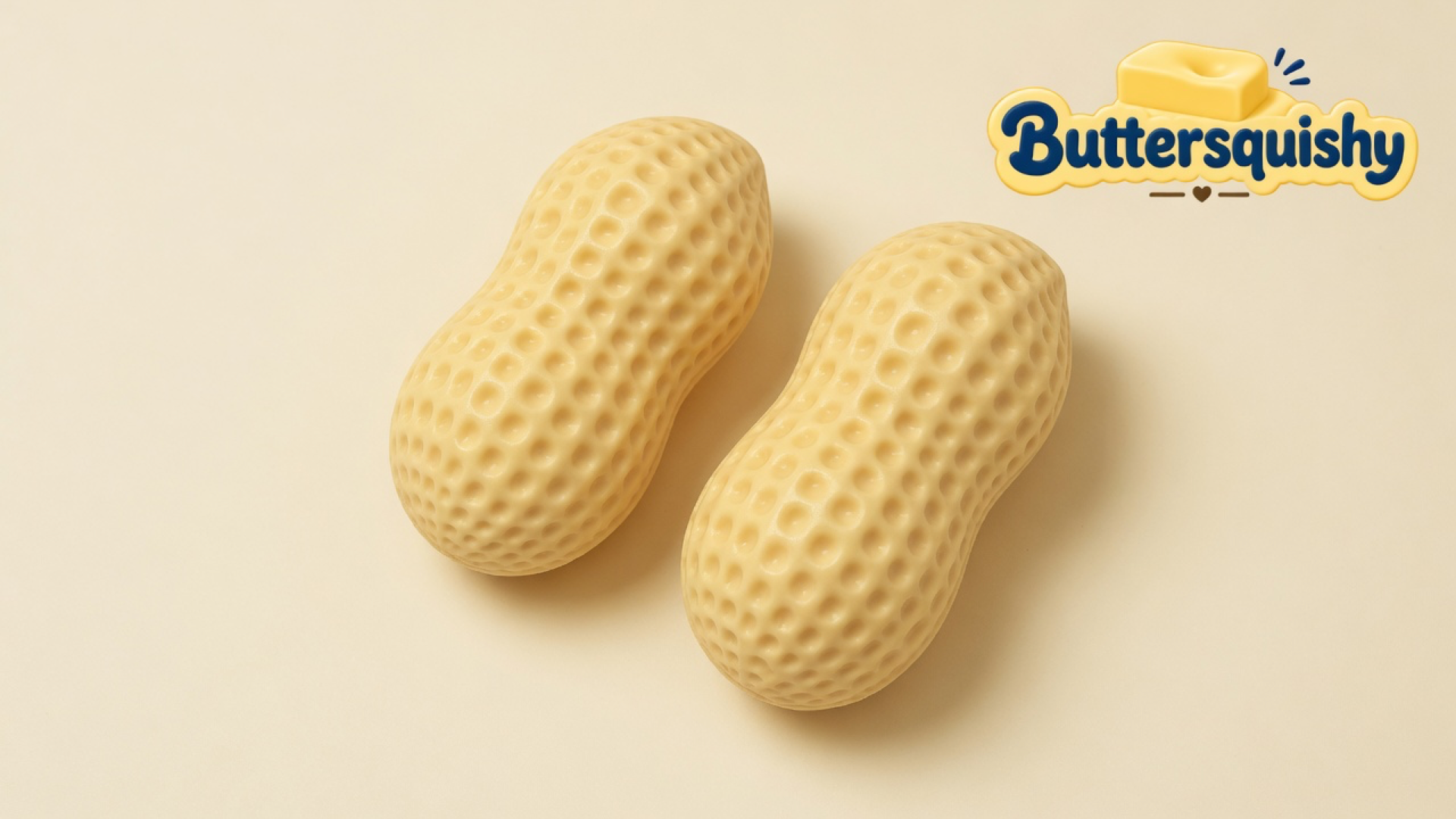 Two pale butter-yellow peanut-shaped squishies with dimpled shells on a light-yellow cream studio, Buttersquishy logo in the upper right