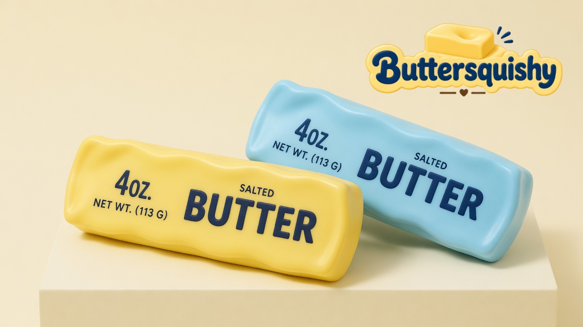 A lemon-yellow butter-stick toy and a powder-blue butter-stick toy on a cream studio block, both printed SALTED BUTTER, Buttersquishy logo at upper right