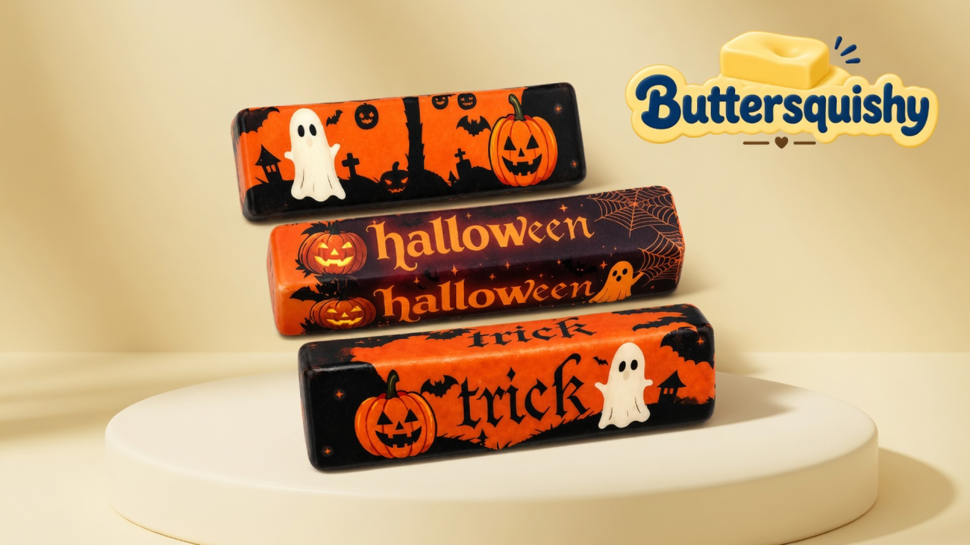 Three Halloween Ghost Butter sticks — graveyard ghost, double halloween script, and double trick print — on a light-yellow cream studio platform, with the Buttersquishy logo in the upper right