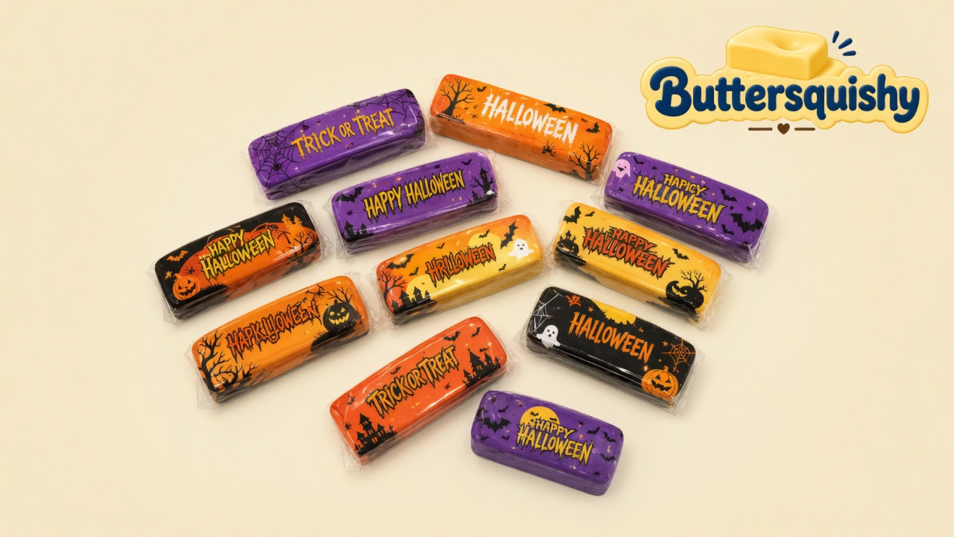 Twelve individually wrapped Halloween Ghost Butter sticks on a cream studio surface, with the Buttersquishy logo in the upper right