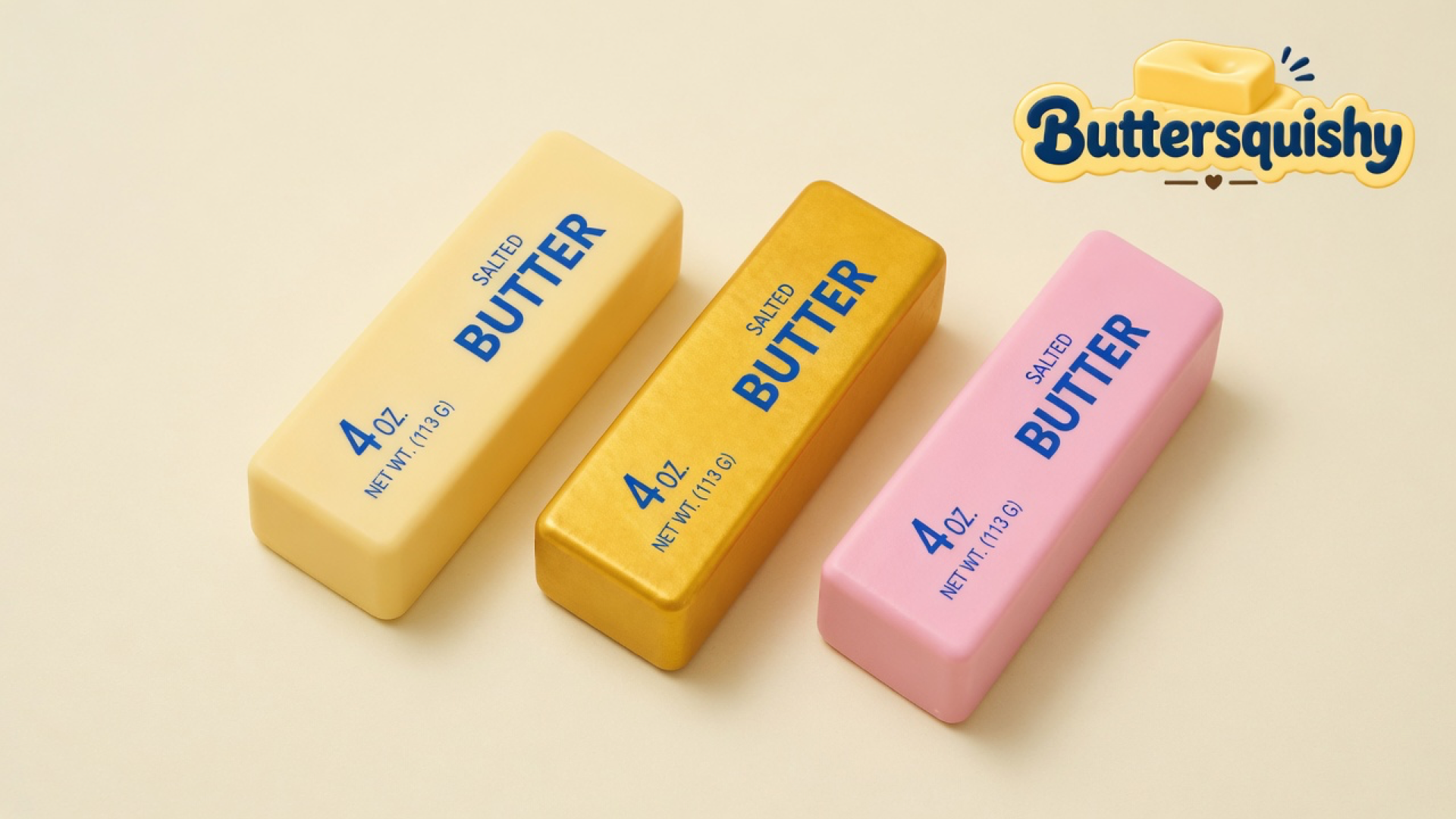 Three cream, gold, and pink Sunset Trio Butter sticks with navy SALTED BUTTER print on a light-yellow cream studio surface, Buttersquishy logo in the upper right
