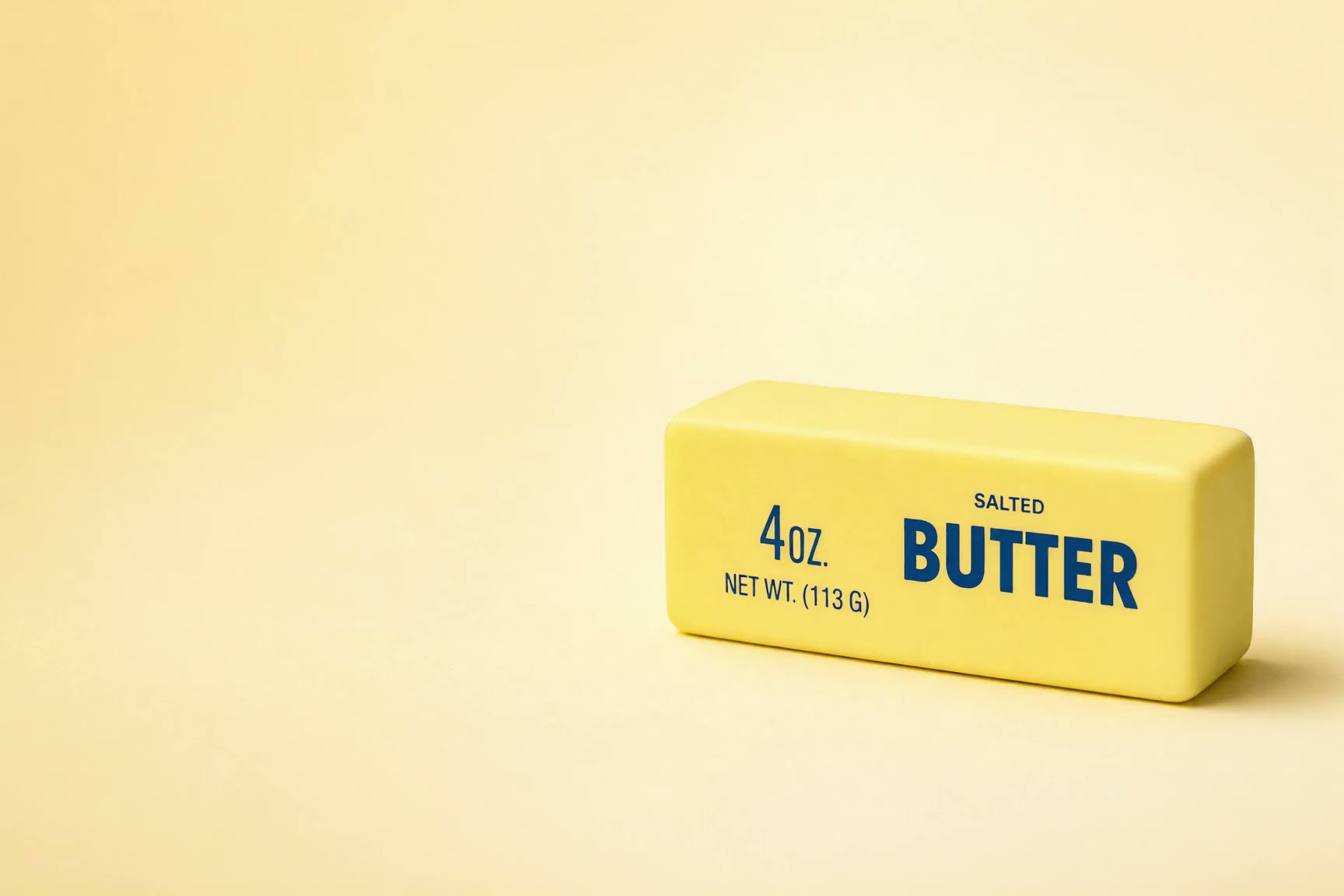 Salted butter stick squishy pressed by a finger on a butter-yellow backdrop